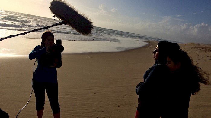 A crew films Zahra and her daughter on a beach in Portugal.
