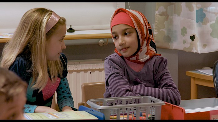 Sahar speaks to a new friend in a classroom in Sweden.